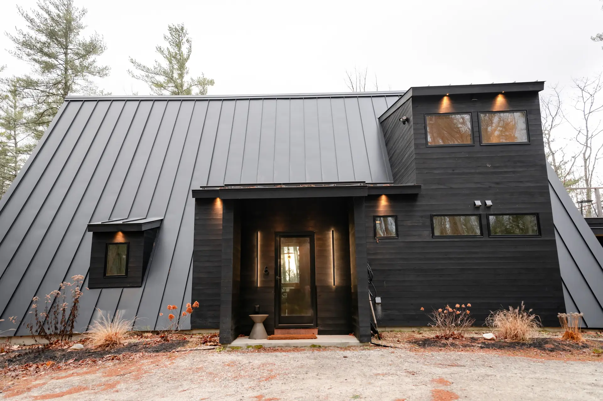 Modern home with a dark standing seam metal roof in a wooded Vermont setting, VT Metal Roofing