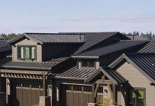 Home with a black standing seam metal roof under clear Vermont sky, VT Metal Roofing