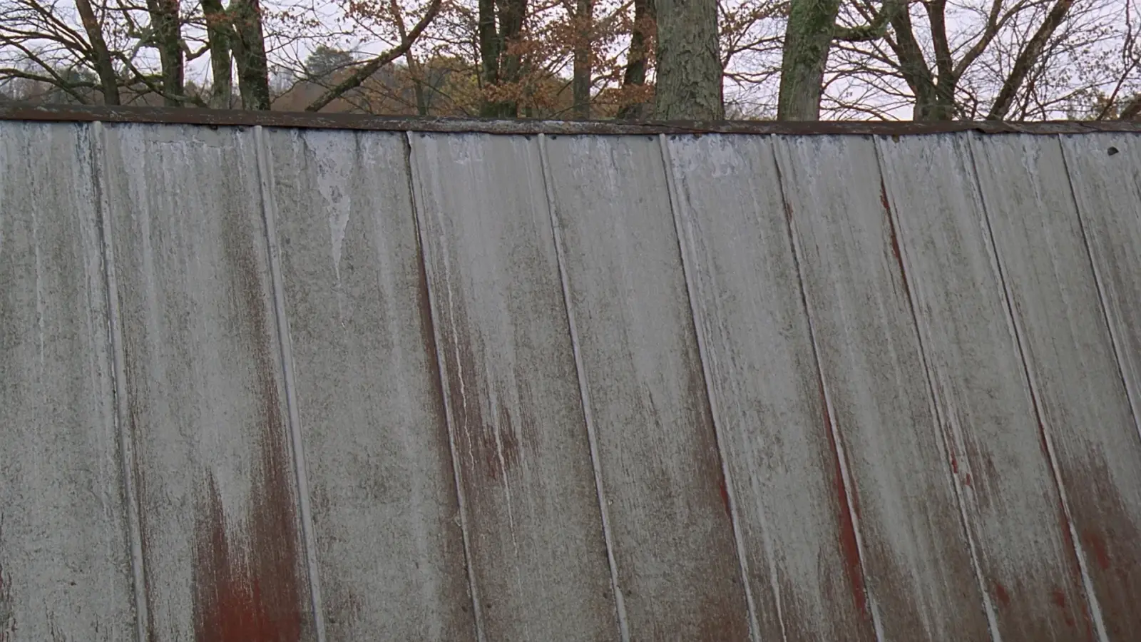 Weathered standing seam metal roof with faded galvanized finish and rust streaks on an older Vermont home